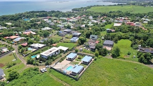 An aerial view of a residential area with houses, roads, and a large body of water in the background.