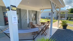 A covered outdoor seating area with tables and chairs, a hammock, and a sign indicating a villa named "Villa Ferry".