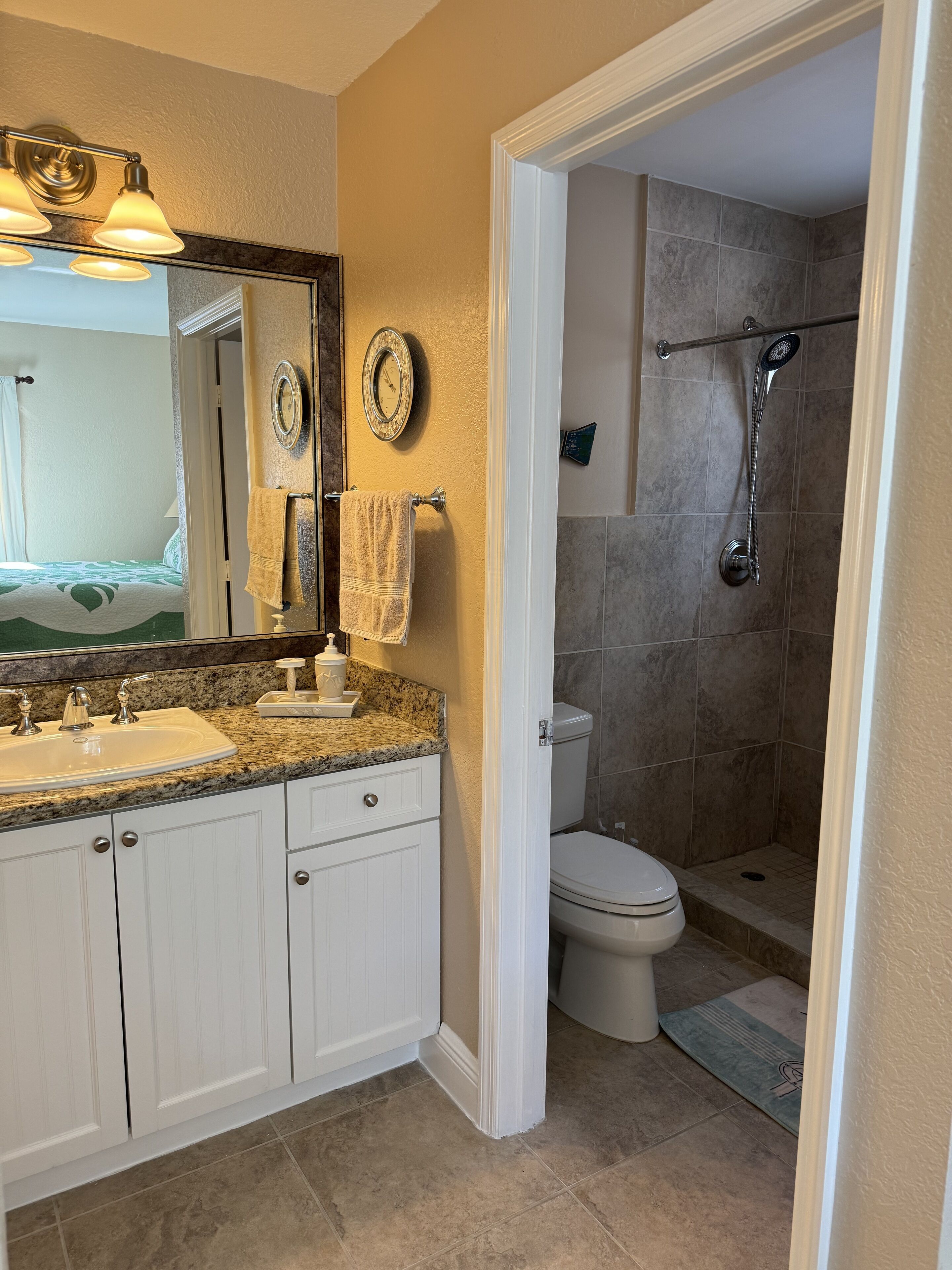 A bathroom with a double sink vanity, a toilet, and a walk-in shower.