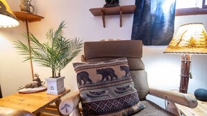 Een gezellige kamer met een houten stoel, een klein tafeltje met een plant en een lamp.