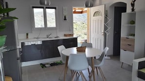 Una cocina moderna con comedor, que incluye una mesa y sillas blancas, horno empotrado y vistas al exterior.
