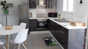 Una cocina moderna con armarios negros, encimera blanca y electrodomésticos de acero inoxidable.