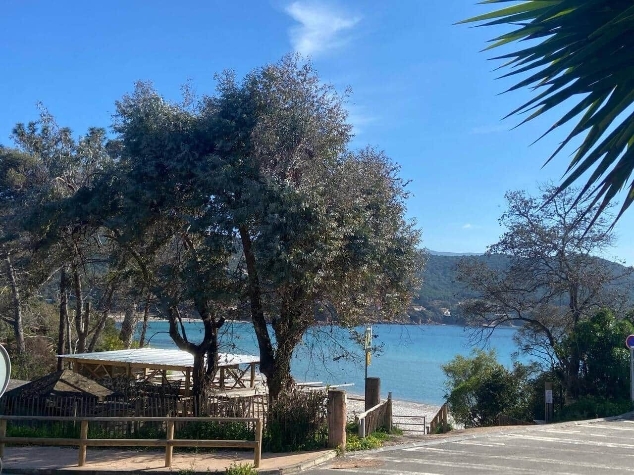 Eine Küstenlandschaft mit einem hölzernen Pavillon, einem gepflasterten Weg und Blick aufs Meer.