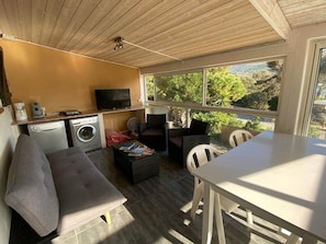 Un espace de vie compact comprenant un canapé, une petite table, un lave-linge et un téléviseur.