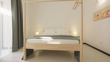 Ein Bett mit Holzgestell und Baldachin, zwei Nachttischlampen, ein Gemälde an der Wand und ein Fenster mit Vorhängen.