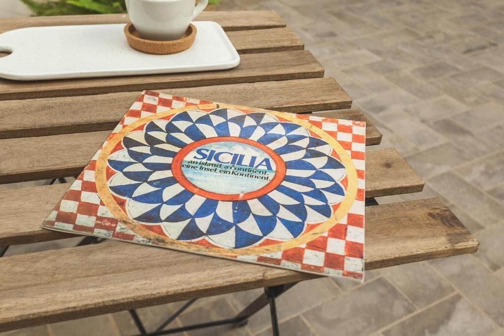 Un tavolo con sottotavola a tema siciliano e una tazzina e un piattino su un sottobicchiere.