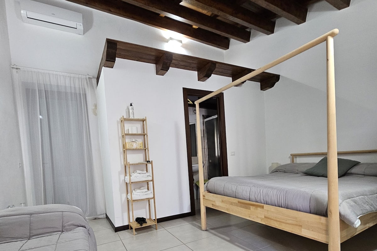 A bedroom with a wooden bed frame, a wooden ladder, a white air conditioner, and a tiled floor.