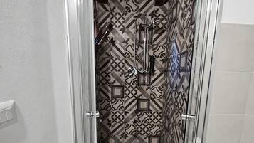 Baño con azulejos estampados, ducha y retrete.