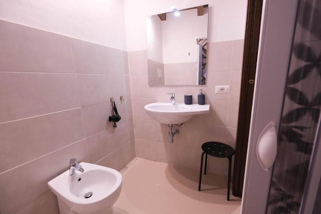 Un baño pequeño con un lavamanos blanco, un bidé y un espejo.