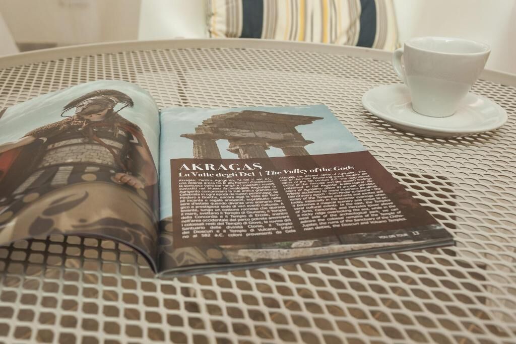 A book open on a table with a cup beside it.