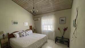 Una camera da letto con un letto grande, un comodino con una lampada, una finestra con persiane e una ventola a soffitto.