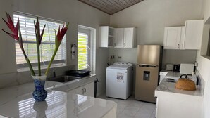Una cucina moderna con mobili bianchi, un frigorifero in acciaio inossidabile, una lavatrice e un piano di lavoro in marmo.