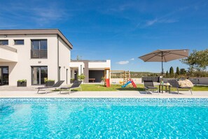 A modern house with a swimming pool, a slide, and lounge chairs. - Villa Blissful Escape - fun for the entire family by MyWaycation (Vrana)