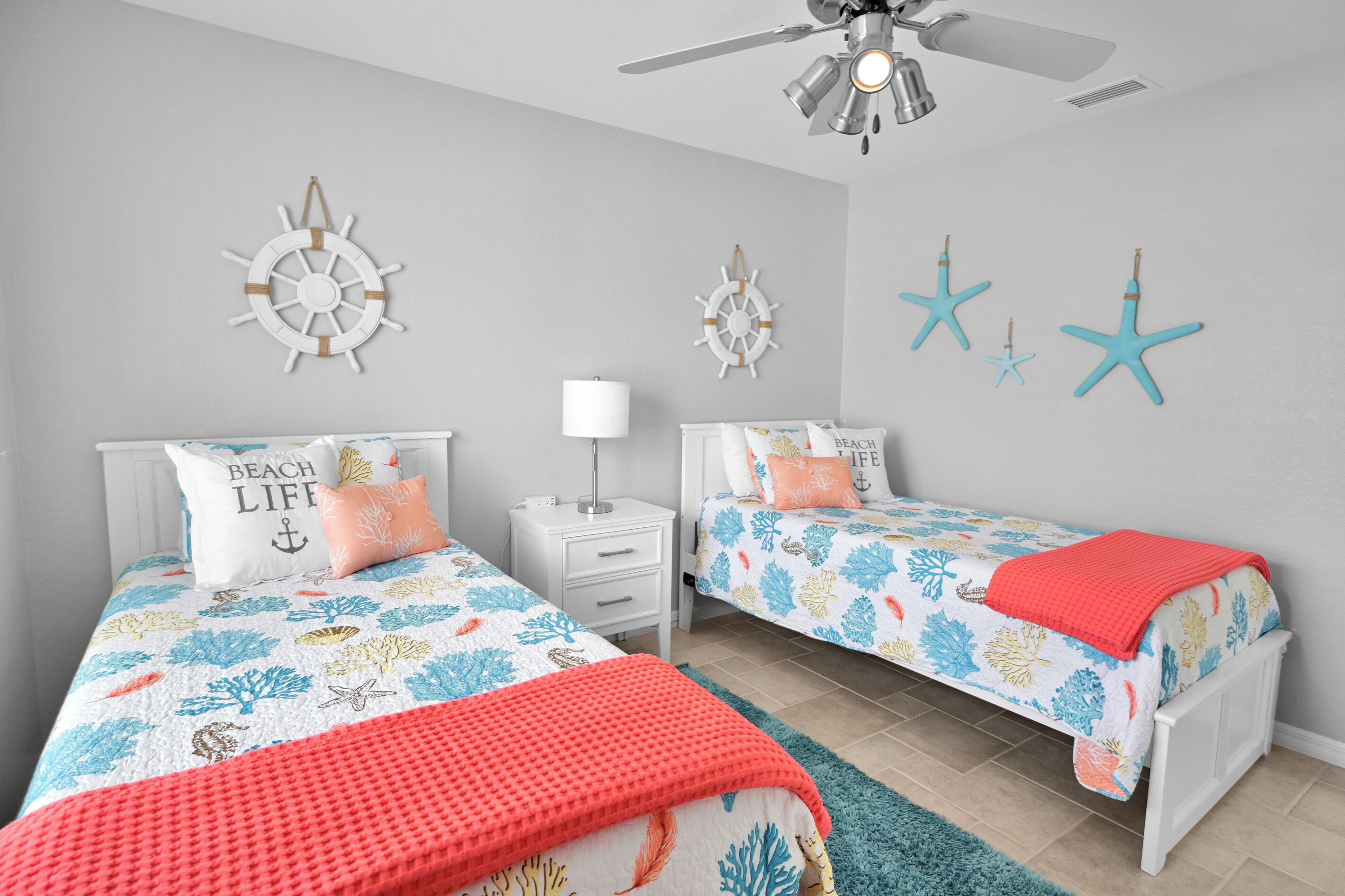 A bedroom with two beds, a ceiling fan, and decorative wall art.