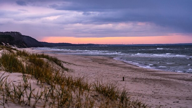 A beach with sand dunes and grass in the foreground, and a cloudy sky in the background. - Beach front home in Rowy with WiFi (Rowy)