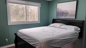 Une chambre à coucher avec un lit, une fenêtre et un tableau accroché au mur.