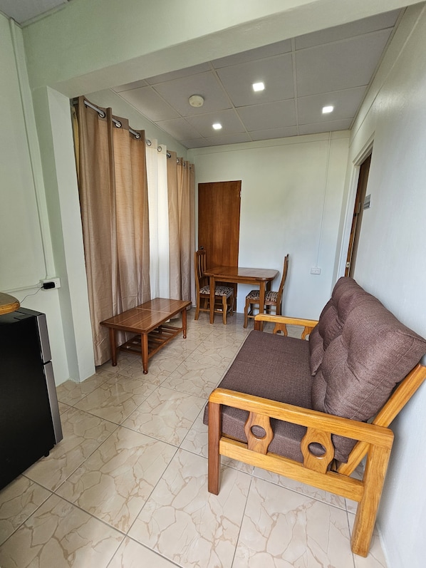 A living room with a wooden sofa, a wooden dining table with chairs, a black cabinet, and a ceiling with recessed lighting. - Beres Vale Apartments (Castara)