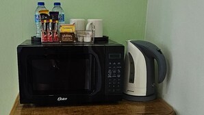 Un petit réfrigérateur doté d’un four à micro-ondes et d’une machine à café placés sur le dessus.
