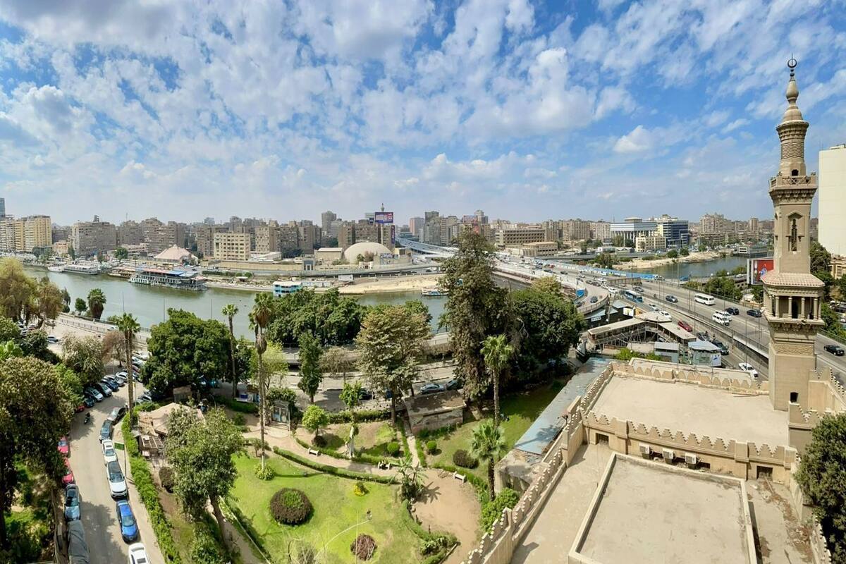 A high-rise building with balconies overlooking a river and a mosque with a minaret.
