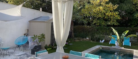 Un patio cubierto con piscina, mobiliario exterior y jardín.