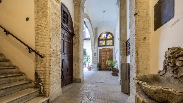 A corridor with a wooden door, a staircase, and a stone lion sculpture. - Palais Romain Historique Piazza Navona AU Coeur DE Rome (Rome)