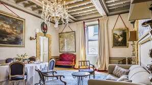 A room with a dining table set for four, a red upholstered chair, a blue patterned armchair, a grey sofa, and a chandelier. - Palais Romain Historique Piazza Navona AU Coeur DE Rome (Rome)