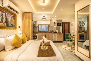 Ein modernes Hotelzimmer mit Bett, einer kleinen Küchenzeile, einem Badezimmer und einem Wohnbereich.