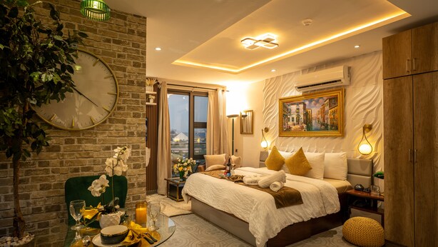 A modern bedroom with a large bed, a dining table, and a green chair. - Luxe rooftop studio in Cantonments steps away from Nekter lounge w/pool & gym  (Accra)