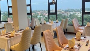 A dining area with tables set for a meal, large windows offering a view of the cityscape, and a modern ceiling design. - Luxe rooftop studio in Cantonments steps away from Nekter lounge w/pool & gym  (Accra)