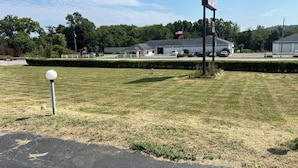 Un motel amb un aparcament, un prat i un edifici amb una bandera.