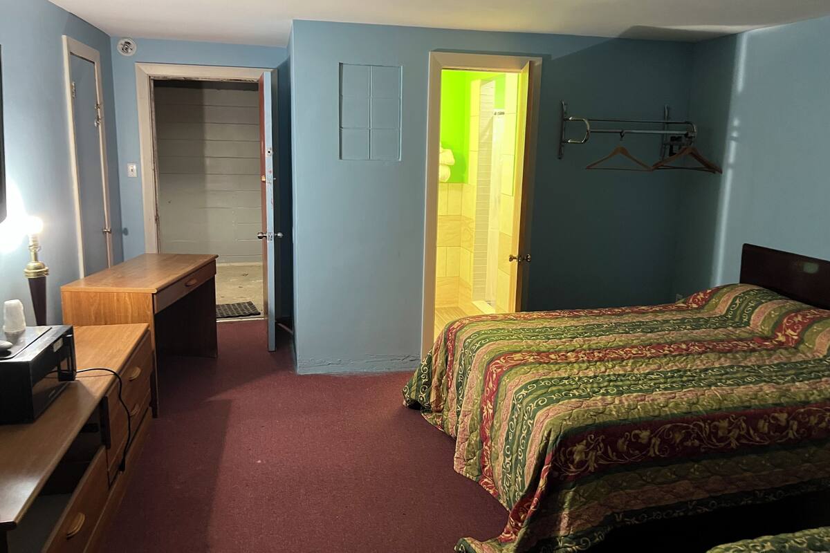 A bedroom with a bed, a desk, a chair, and a wardrobe.