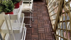 A small, enclosed balcony with a tiled floor, a white sink, and potted plants.