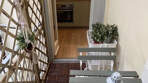 A narrow corridor with a wooden lattice door, a small table with a lantern, and a potted plant.