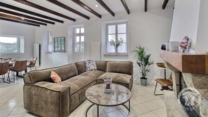 Een moderne woonkamer met een hoekbank, een ronde salontafel en een stenen open haard.