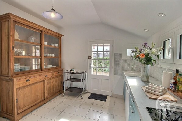 A modern kitchen with a wooden cabinet, a rolling pin, and a vase of flowers.