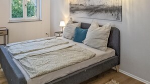 A bed with a grey frame, multiple pillows, and a blanket. - 3 bedroom gorgeous apartment in Bad Heilbrunn (Bad Heilbrunn)