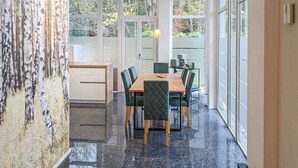 A dining area with a wooden table and chairs, large windows, and a view of trees. - 3 bedroom gorgeous apartment in Bad Heilbrunn (Bad Heilbrunn)
