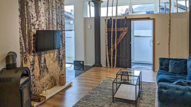 A modern living room with a fireplace, a television, and a blue sofa. - 3 bedroom gorgeous apartment in Bad Heilbrunn (Bad Heilbrunn)