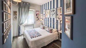 Une chambre à coucher avec un lit, des rideaux, un radiateur et des tableaux accrochés au mur.