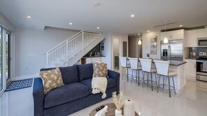 A modern living room with a sofa, a coffee table, and a kitchen area with a bar and seating. - New Listing Sea Side Paradise.  Best of Key Largo! (Key Largo)