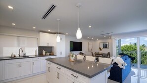 A modern kitchen with white cabinetry, a large island, pendant lighting, and a view to a balcony. - New Listing Sea Side Paradise.  Best of Key Largo! (Key Largo)
