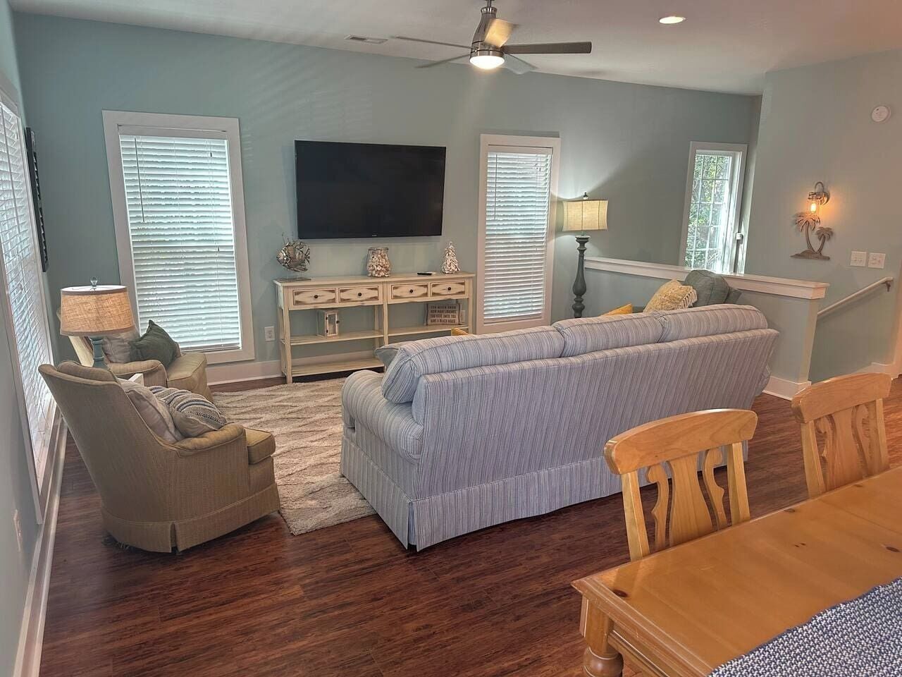A living room with a sofa, armchair, and wooden dining table.
