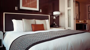 A hotel room with a large bed, a headboard, a bedside table with a lamp, and a framed picture on the wall. - Limited Edition (Addis Ababa)