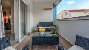 Un balcón con mesa, sillas, sofá y planta en maceta.