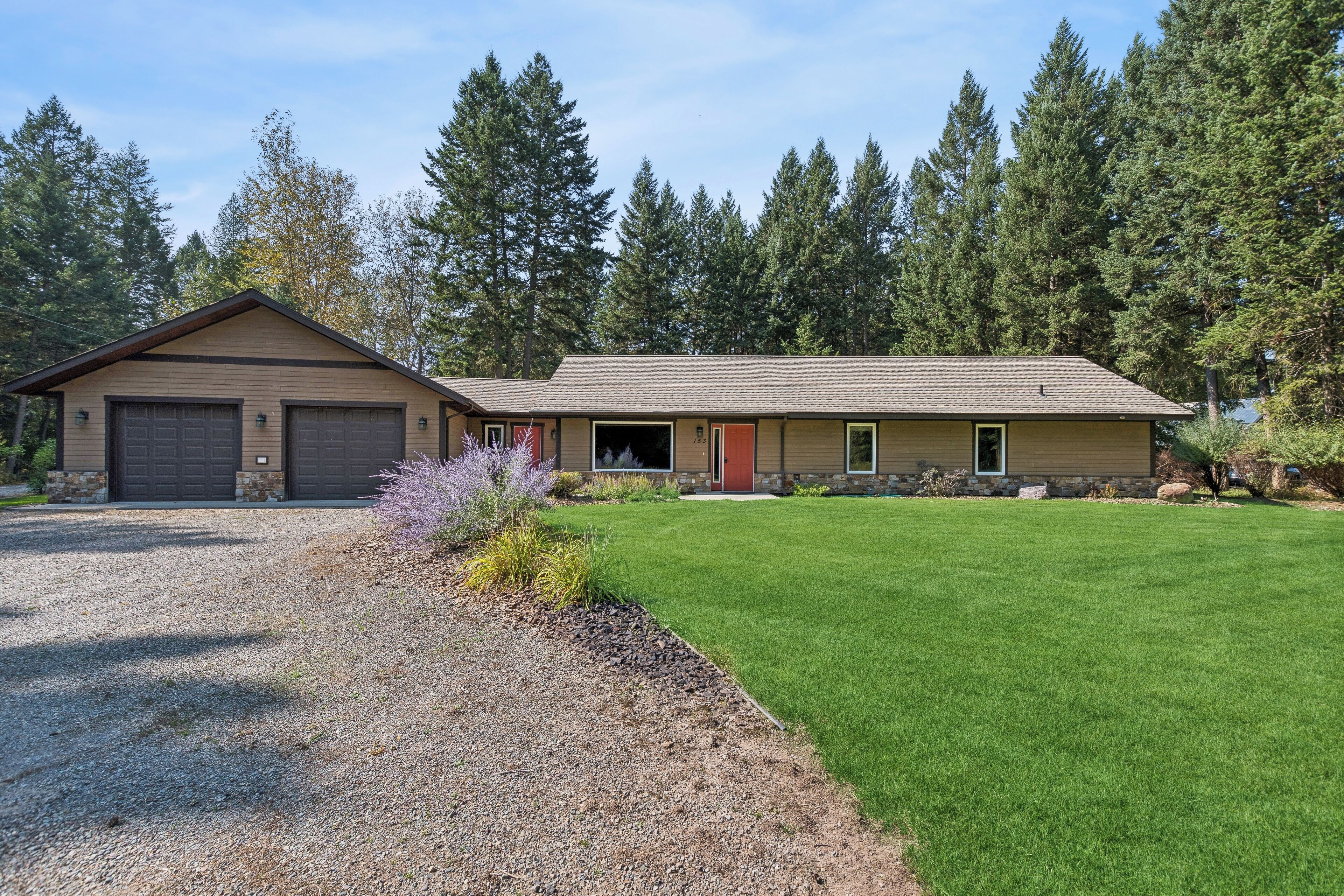 A two-story house with a garage, a front porch, and a well-maintained lawn.