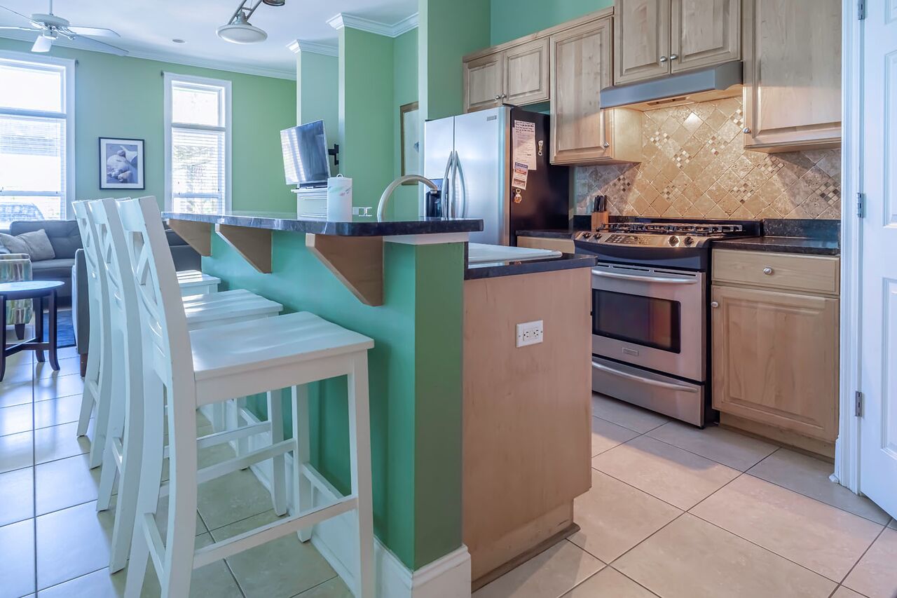 A kitchen with a central island, wooden cabinets, a stainless steel refrigerator, and a stove.