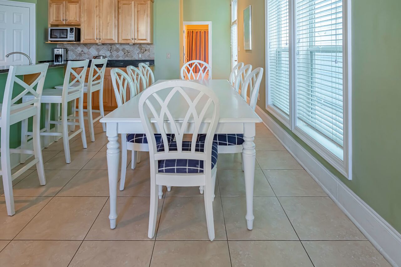 A dining area with a white table and chairs, a microwave, and a kitchen counter.