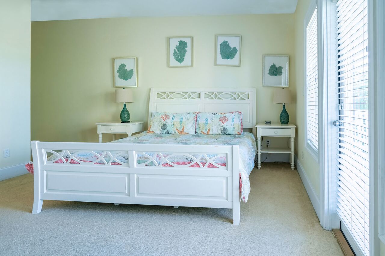A bedroom with a white bed, two bedside tables, and three wall-mounted picture frames.