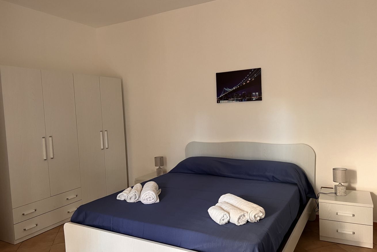 Un dormitorio con cama, mesita de noche, armario y un cuadro en la pared.