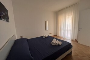 Ein Einzelbett mit dunkelblauer Bettdecke und darauf gerollten Handtüchern.